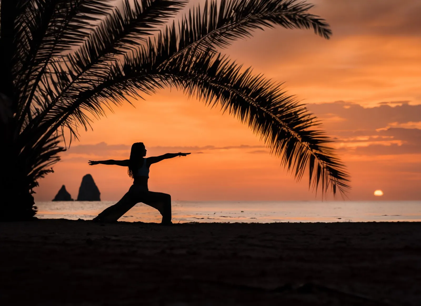 A yoga posture beside a tropical beach at sunset