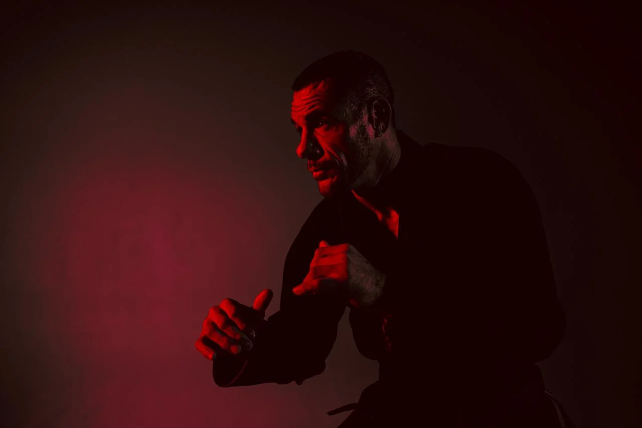 A practitioner in a black gi under low red light